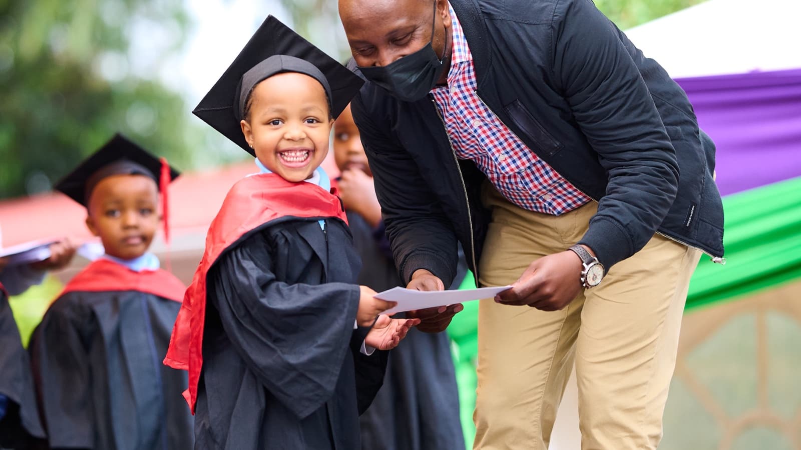 A smiling Kigwa Ridge School early-years graduate receiving a certificate